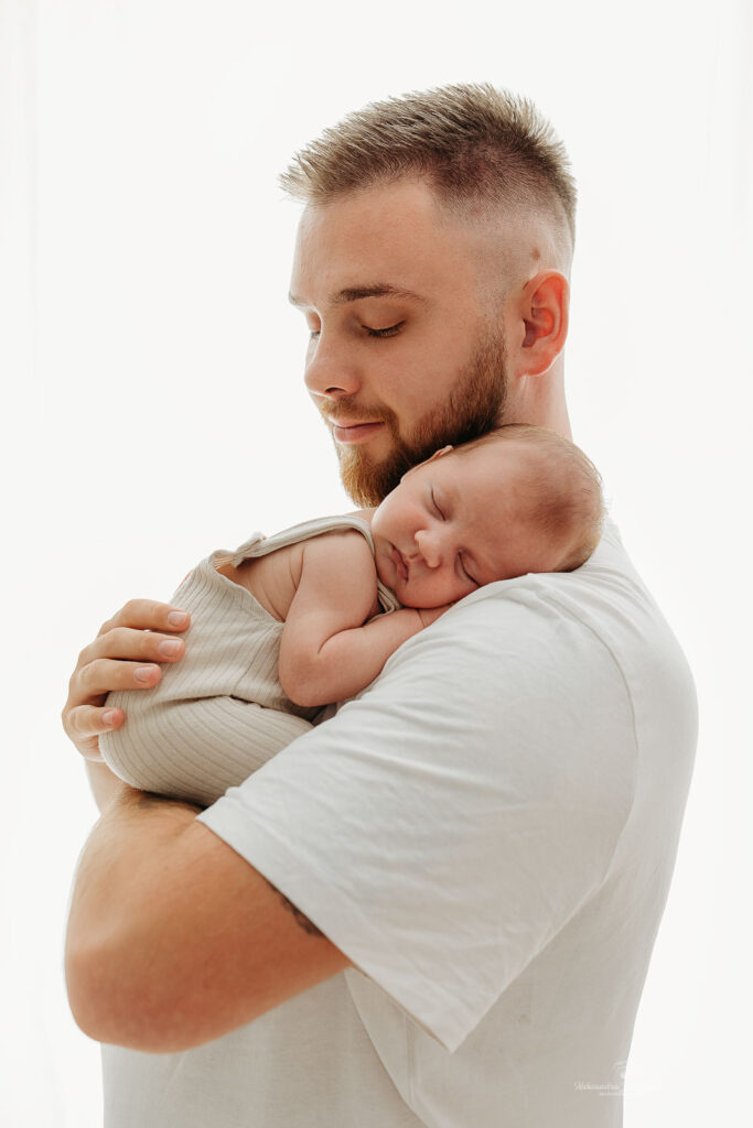 tata w beżowej koszuli przytula dziecko do zdjęcia rodzinnego