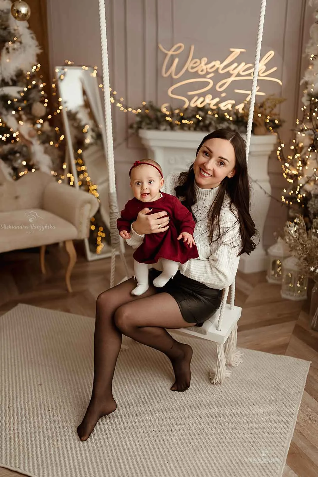 Mama z niemowlakiem na huśtawce w świątecznej aranżacji – sesja świąteczna studio Noworodkowo Warszawa